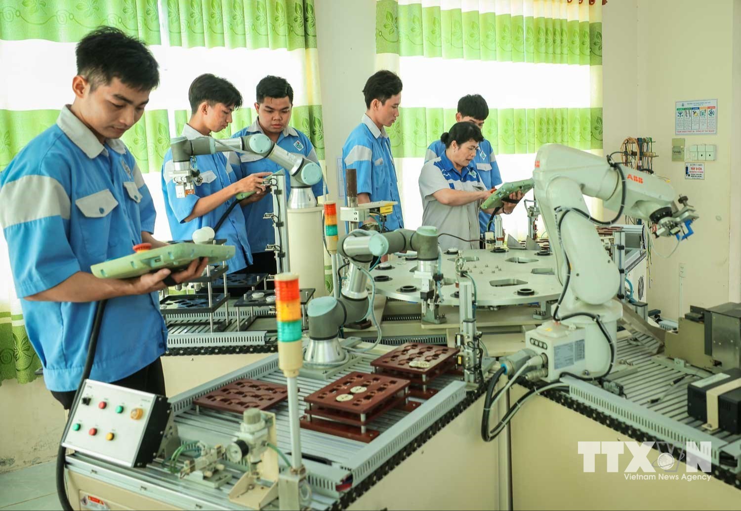 Thạc sĩ Phan Hoài Loan – giảng viên khoa Điện tử đang hướng dẫn sinh viên nghề Cơ điện tử vận hành cánh tay Robot, qua đó giúp sinh viên hiểu và gắn lý thuyết với thực hành và ứng dụng công nghệ vào nghiên cứu, sáng tạo robot. (Ảnh: Hoàng Hiếu/TTXVN)